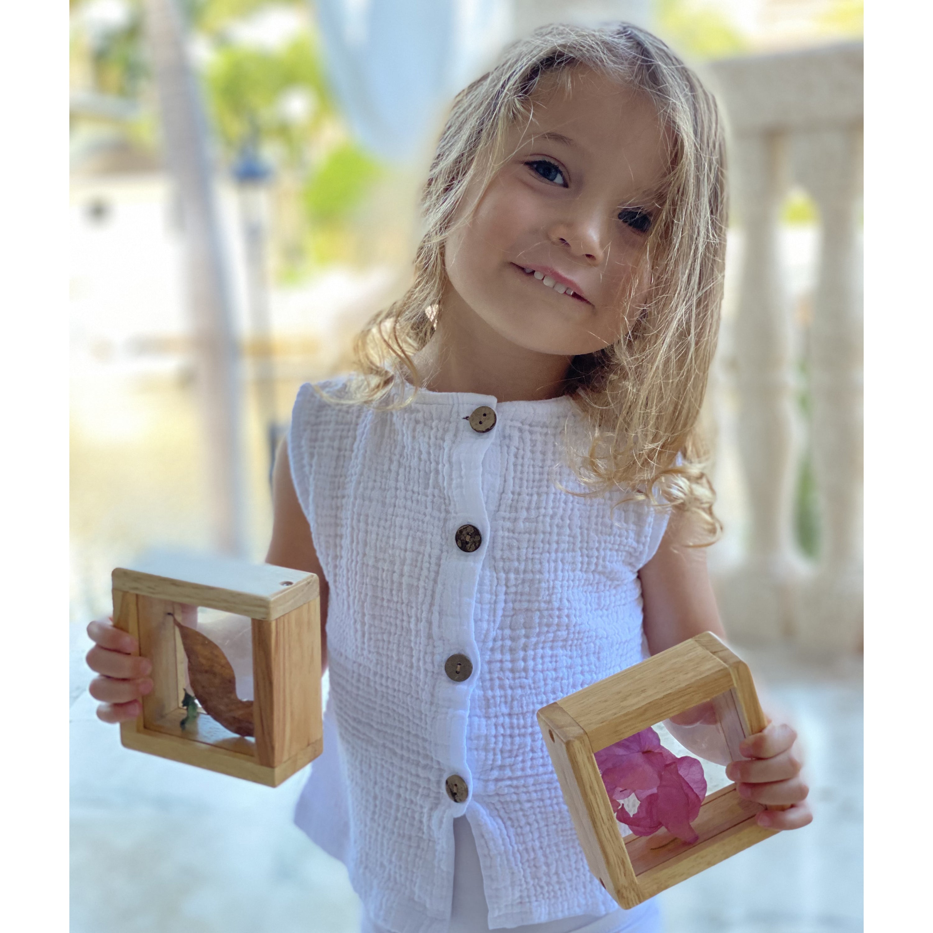 Young girl holding two wooden picture frames outdoors
