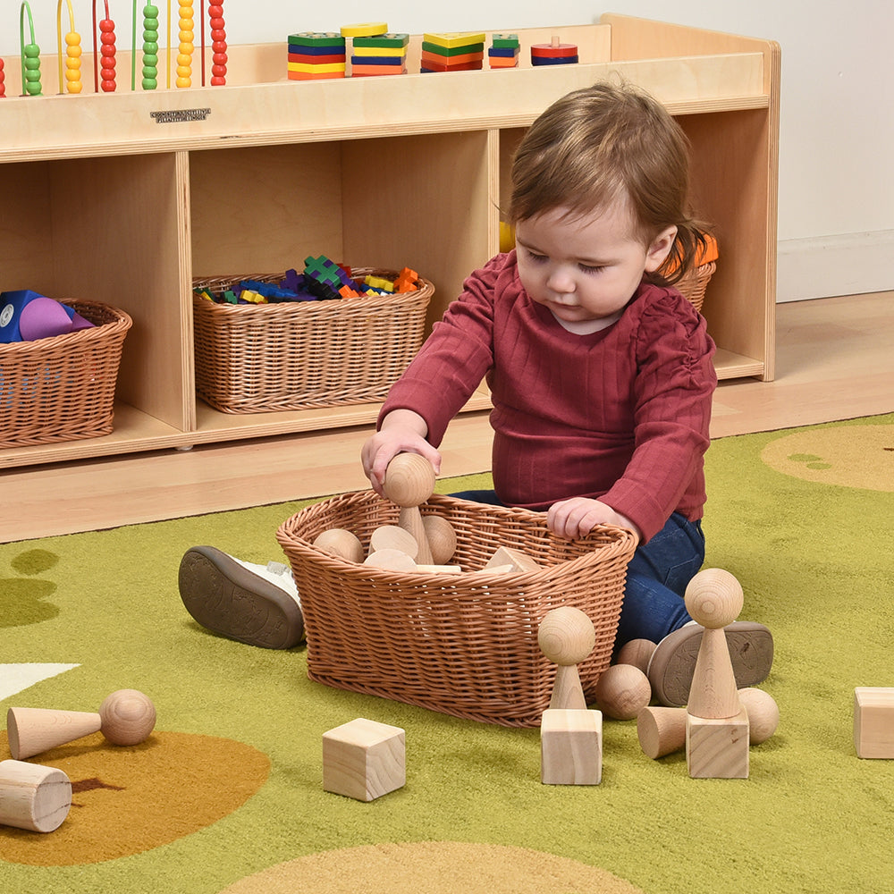 Infant exploring blocks in a basket on the carpeted floor of classroom