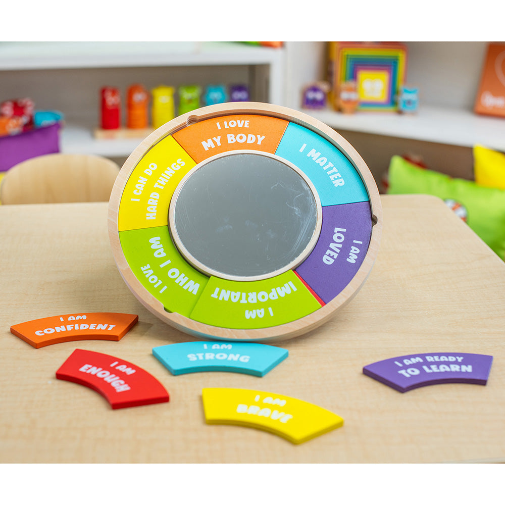 Colorful educational wheel with positive affirmations on a table in a classroom setting.