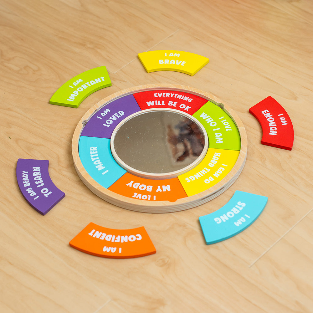 Circular mirror with motivational phrases on a wooden floor