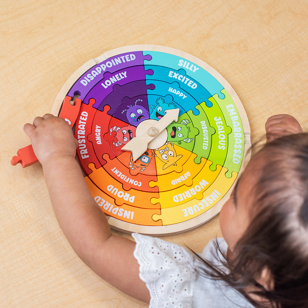 Child playing with a colorful emotion puzzle on a wooden surface