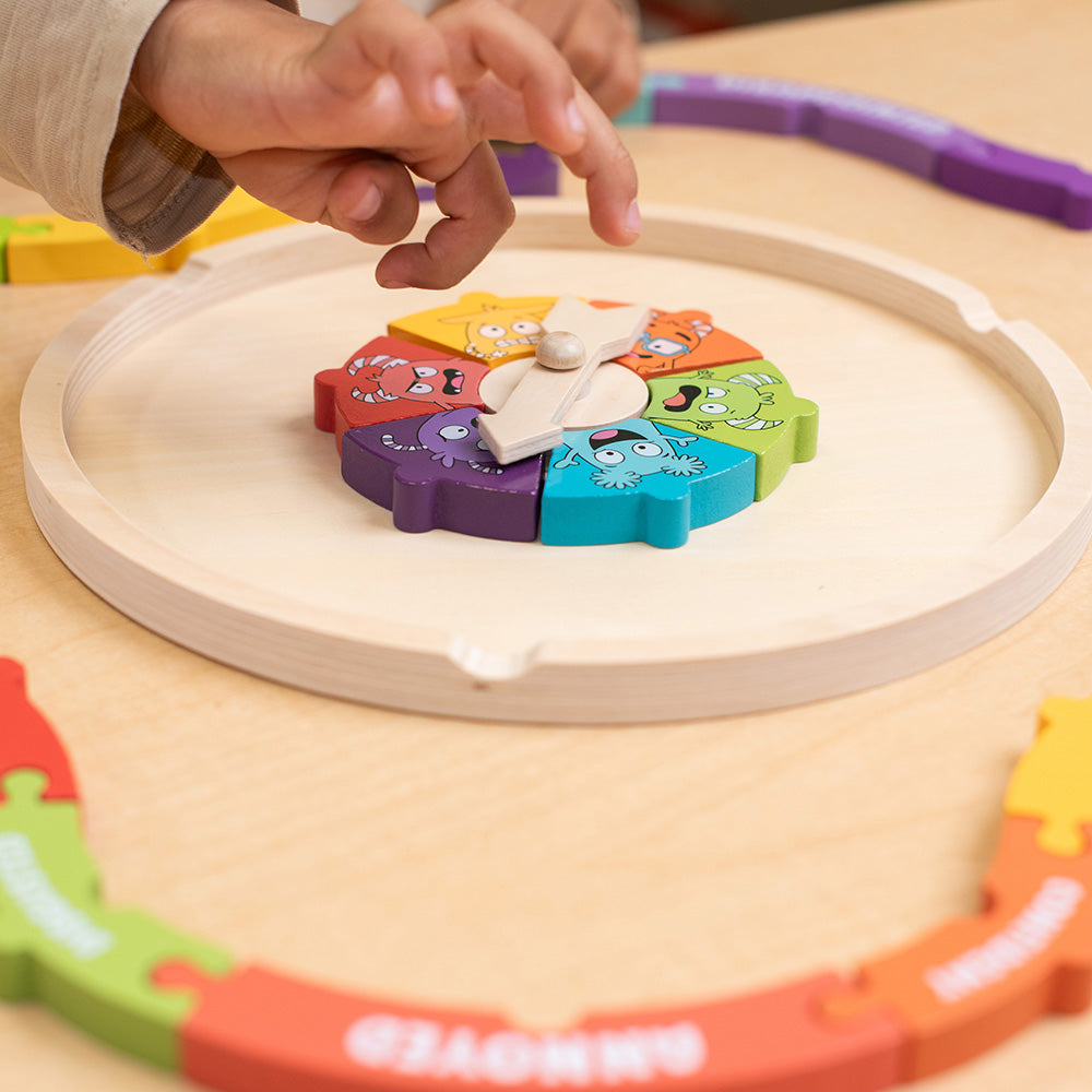 Child's hand interacting with a colorful toy on a wooden surface.