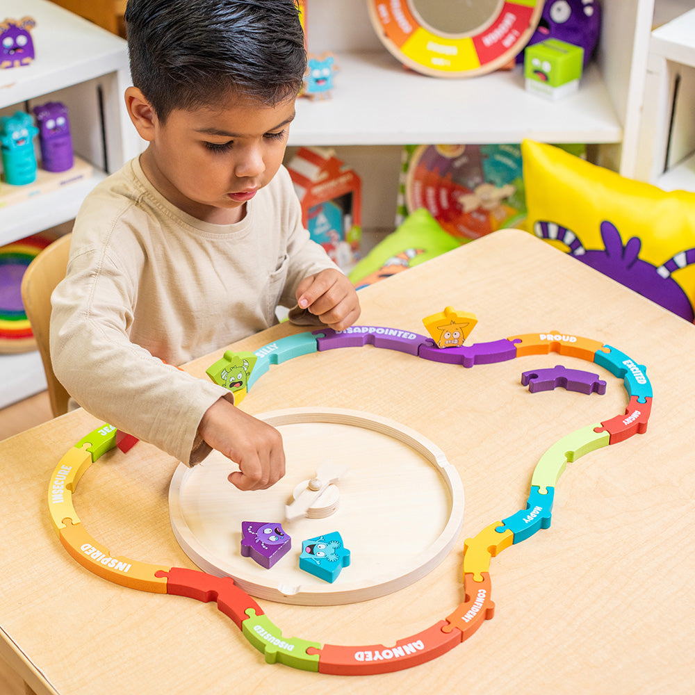 Child playing with a colorful puzzle toy on a table in a playful indoor setting.