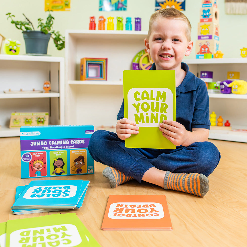 Child holding a 'Calm Your Mind' card in a classroom setting with educational materials around.