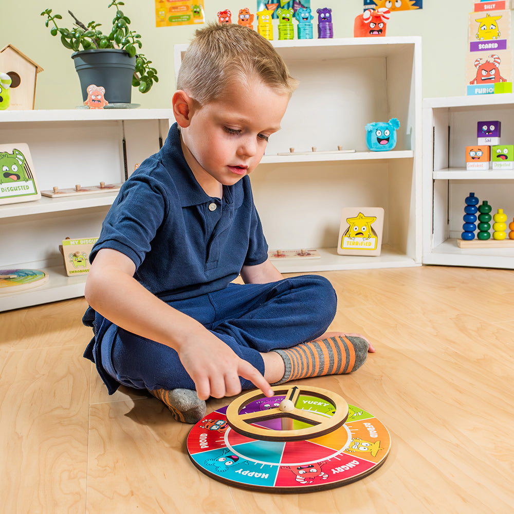 Child playing with a colorful educational toy on a wooden floor in a room with shelves filled with toys.