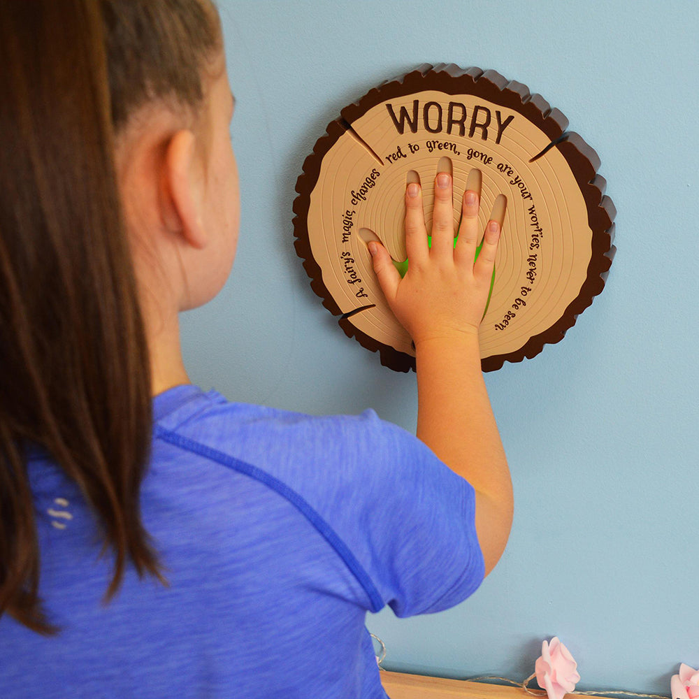 Child interacting with a circular wooden board on a light blue wall