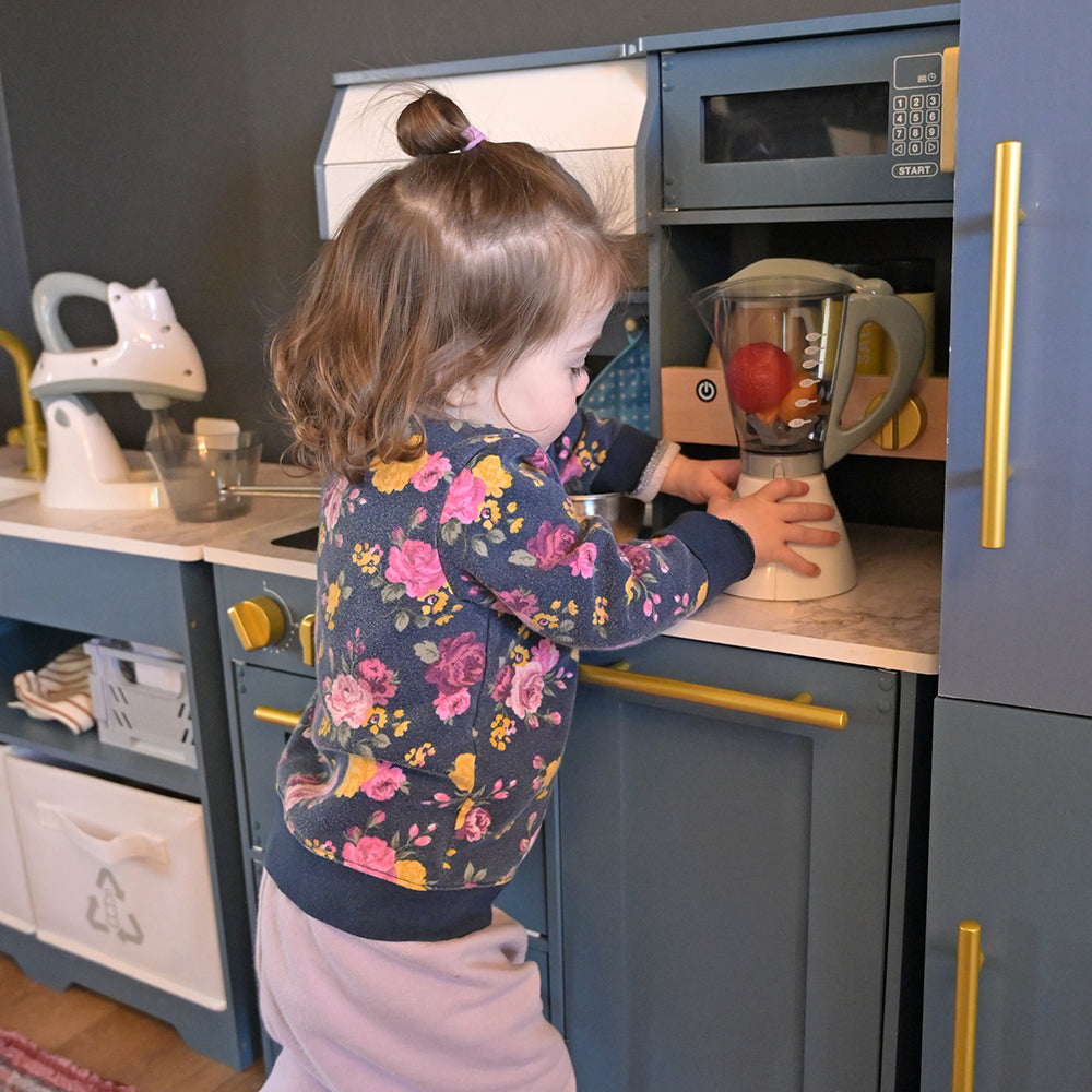 Toddler Adding Toy Appliances to Pretend Kitchen