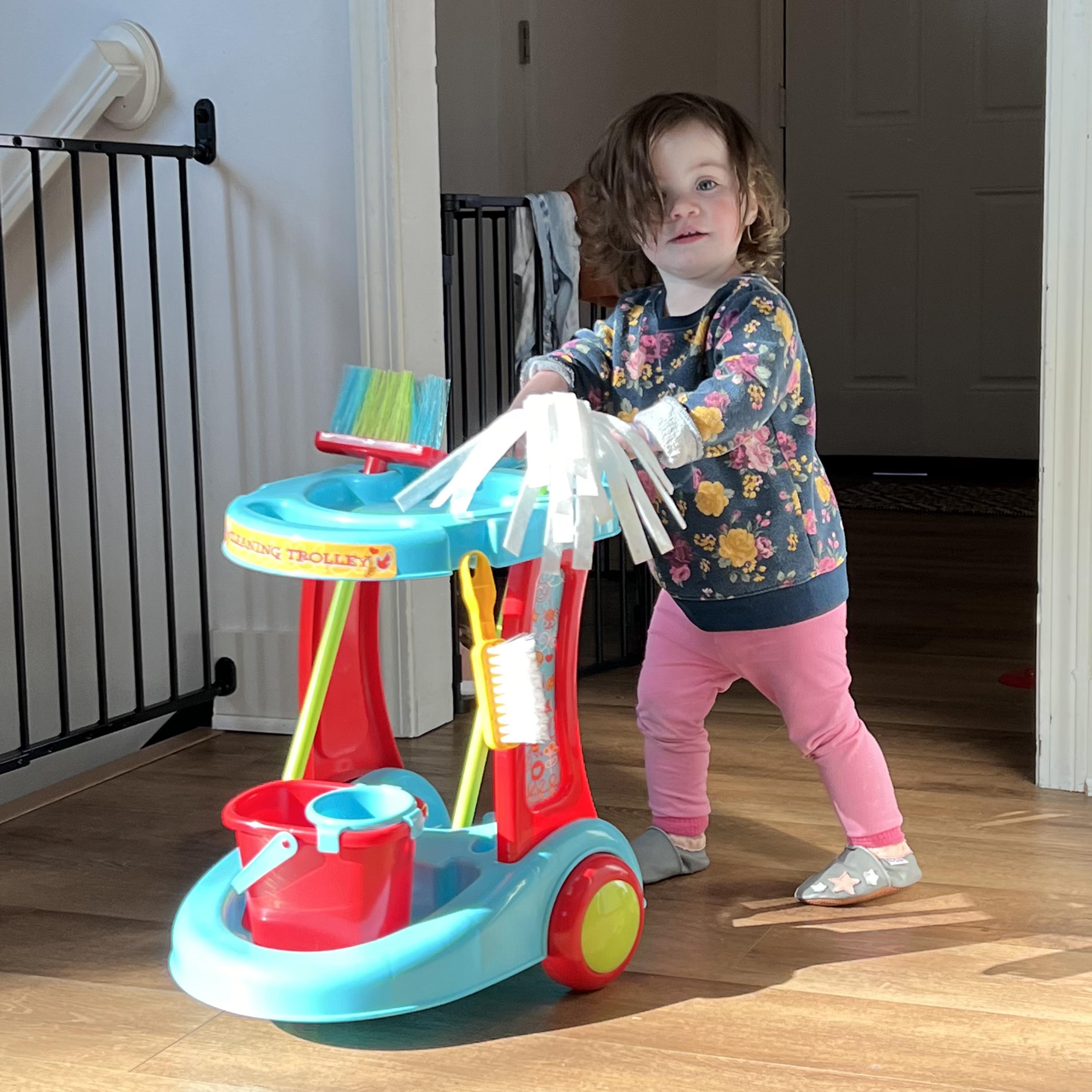 Child playing with a colorful toy cleaning set in a home setting