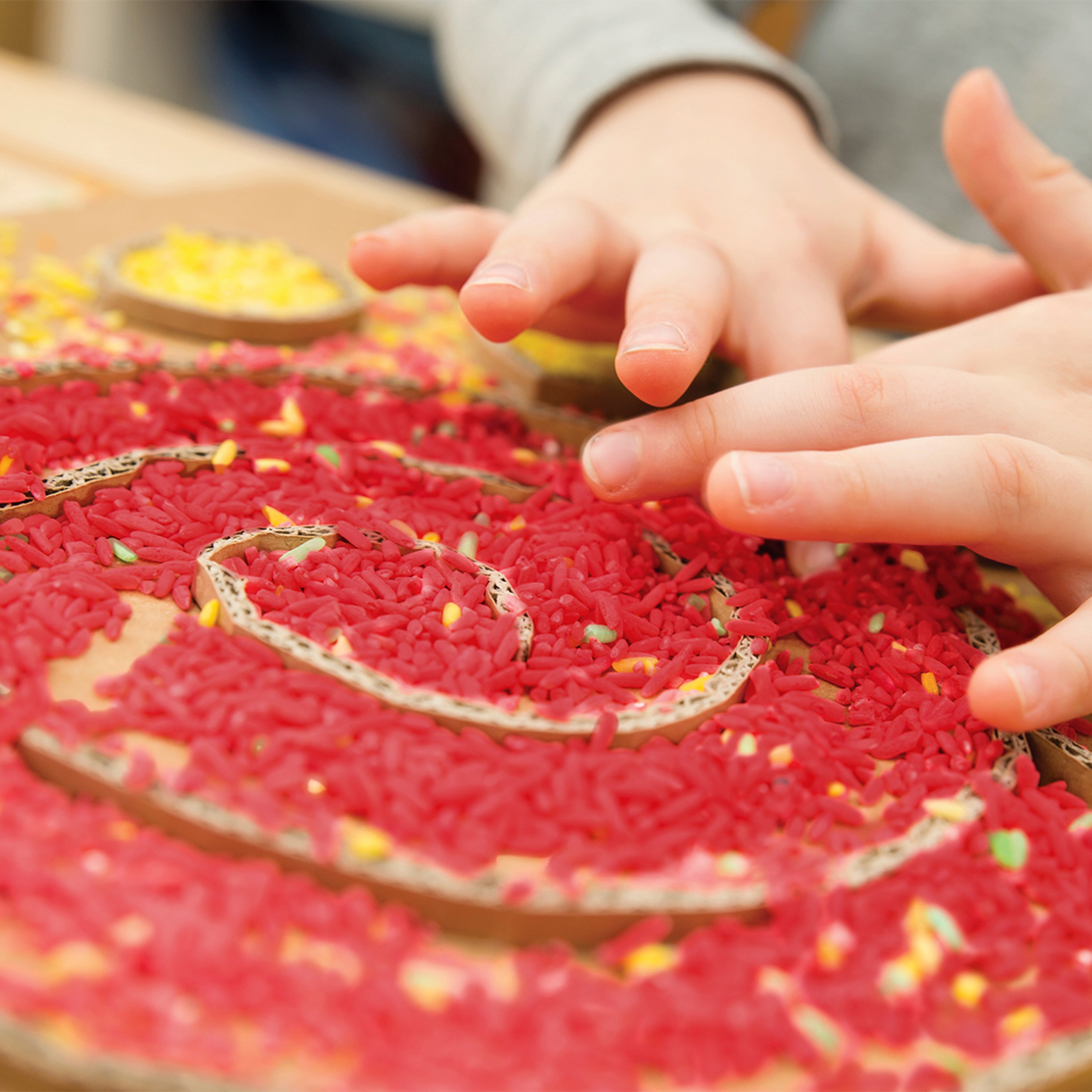 Close-up of a child's hands interacting with a red textured surface