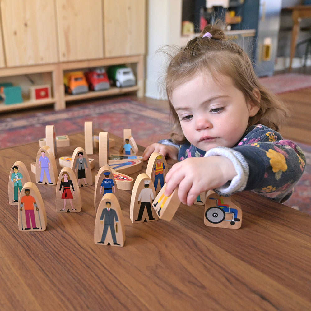 Toddler Playing with Diverse Wooden Community Figures