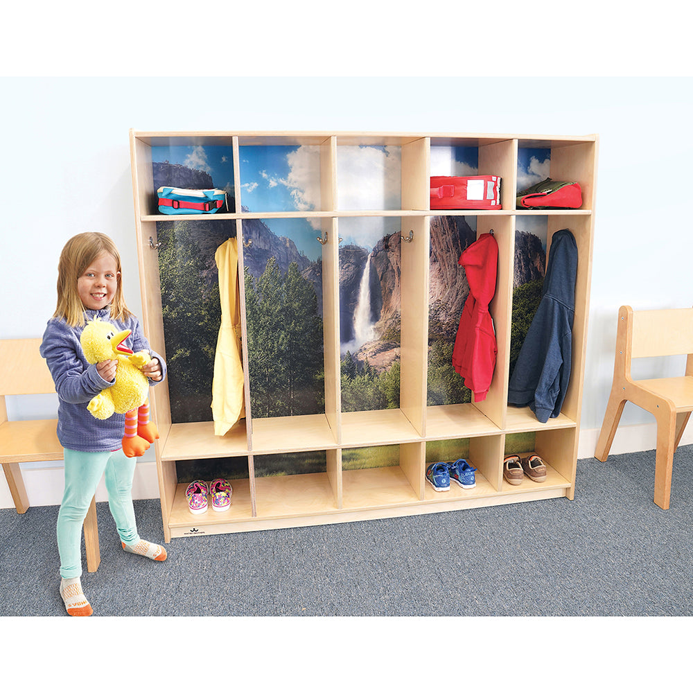 Child standing next to a wooden locker with nature-themed background in a classroom setting.