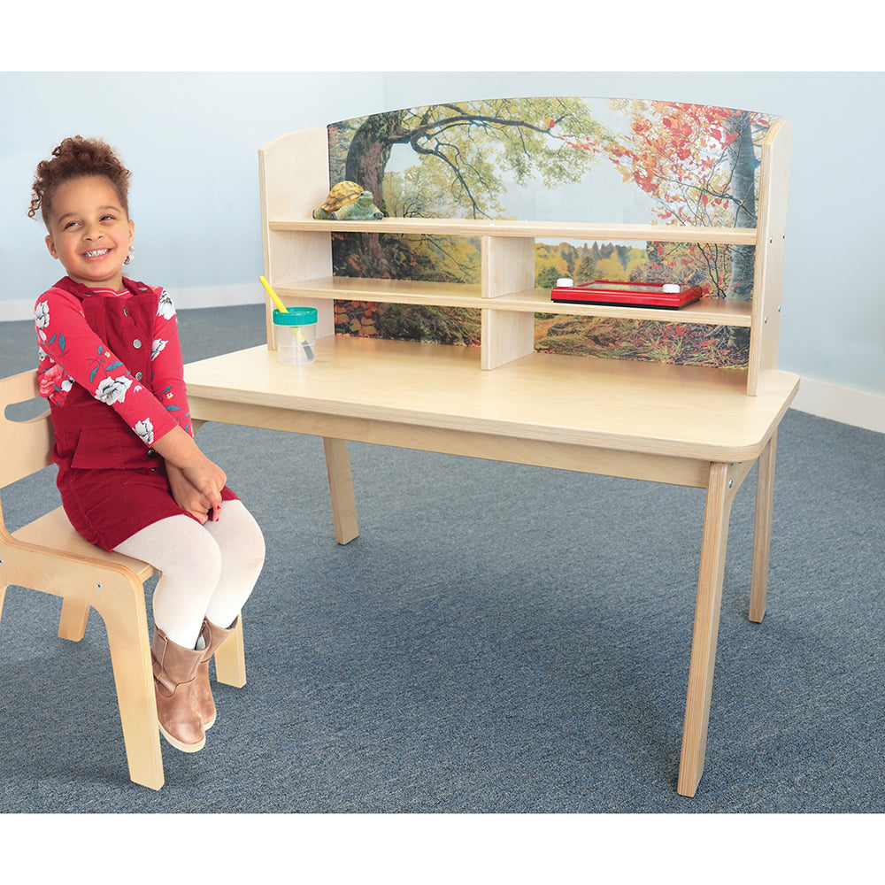 Child sitting at a wooden desk with shelves against a light blue wall.