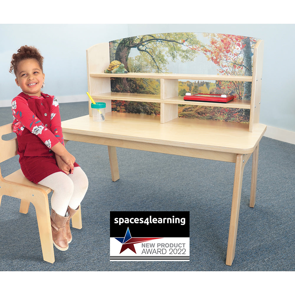 Child sitting on a chair next to a wooden desk with shelves, featuring 'spaces4learning' award badge.