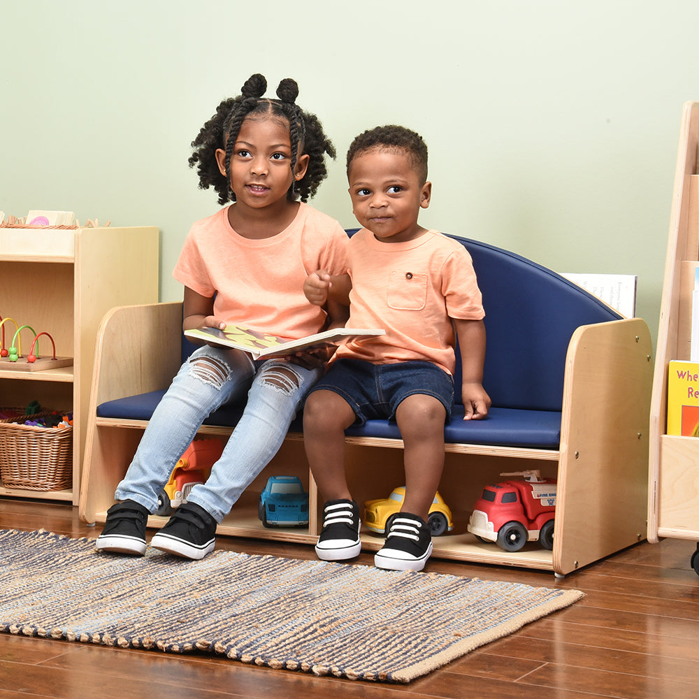Two Kids Reading a Book while Seated on Classic Classroom Couch in the classroom