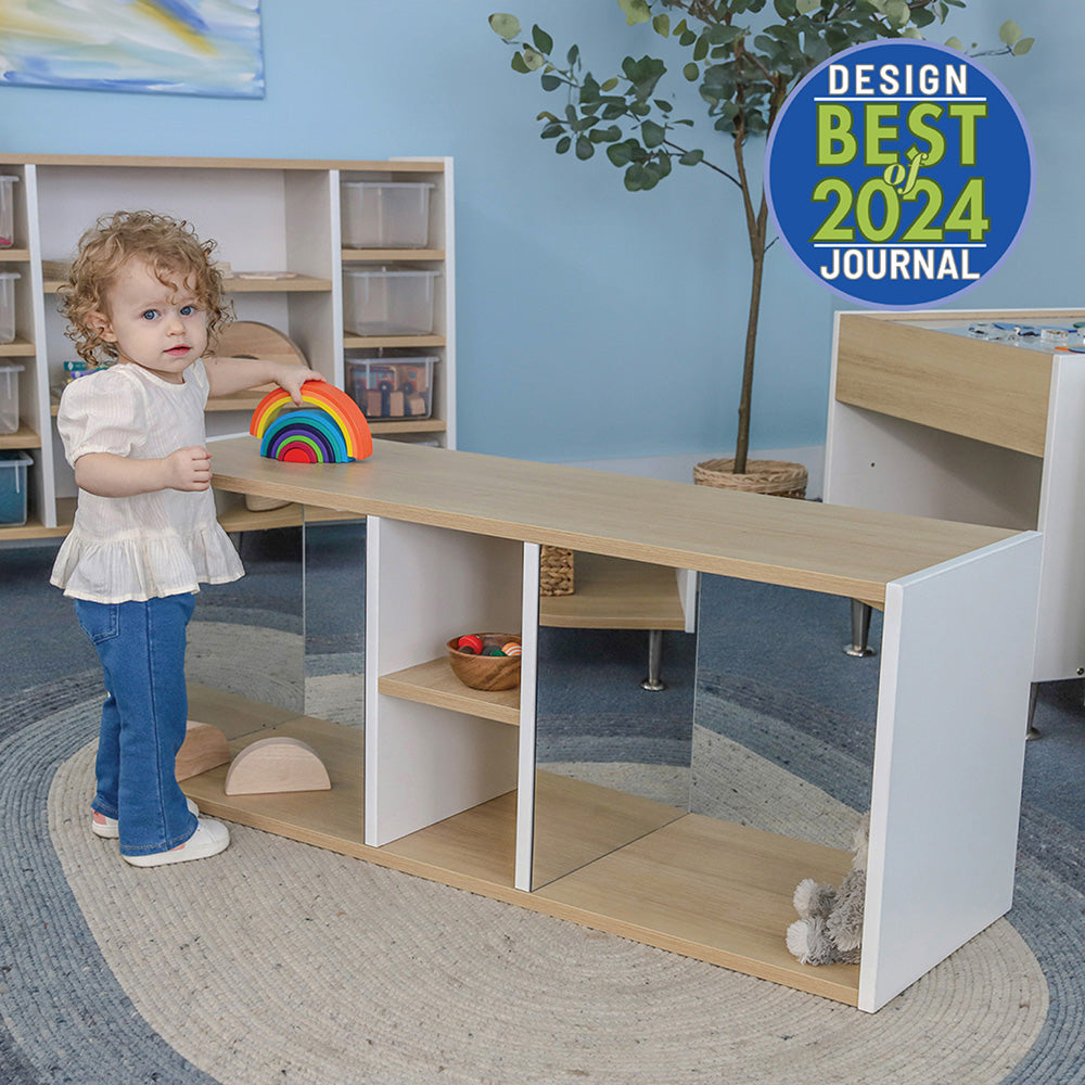 Child playing with a rainbow toy in a classroom setting with educational furniture.