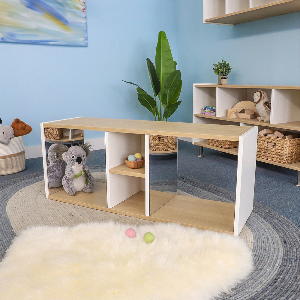 Children's playroom with a wooden shelf, toys, and a plant against a blue wall.