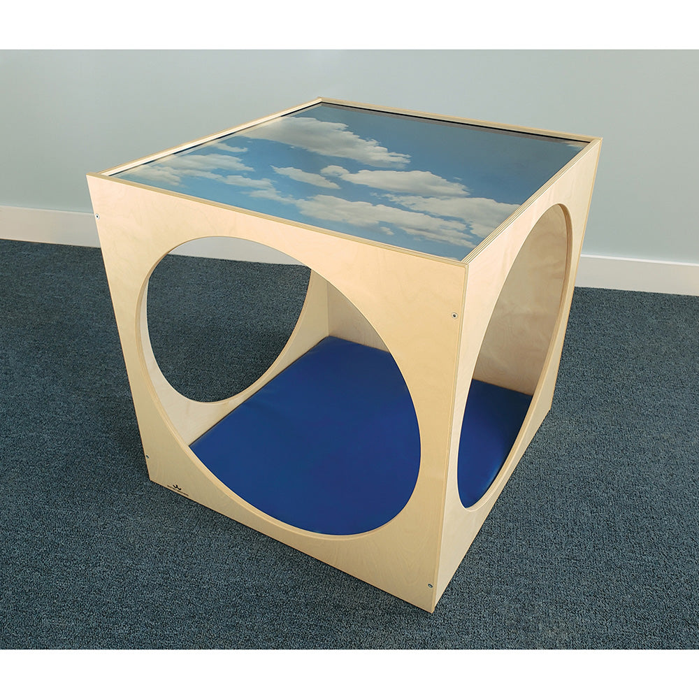 Wooden cube with sky and cloud design on top, blue interior, on a gray floor.