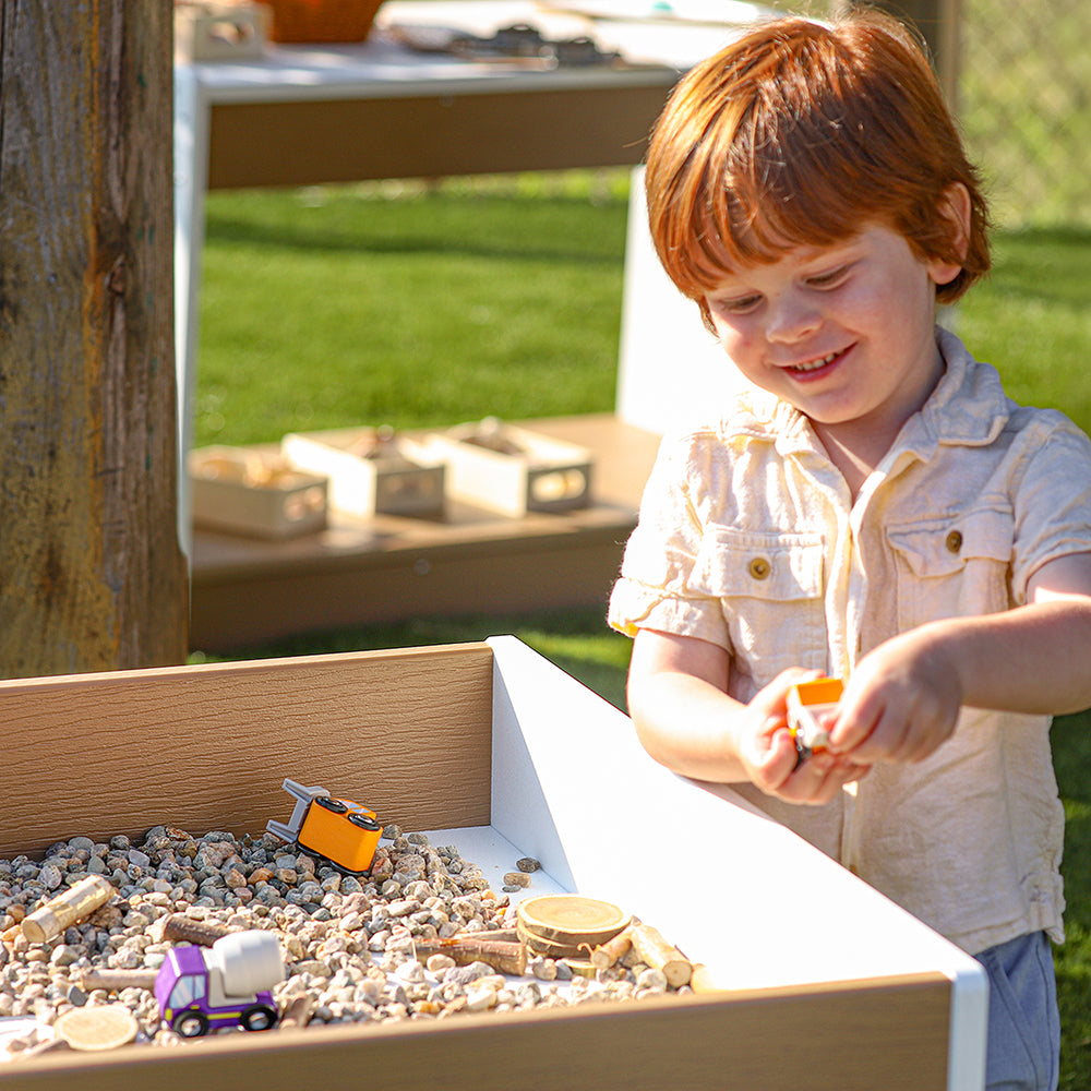 Child playing with toys in a sand box outdoors