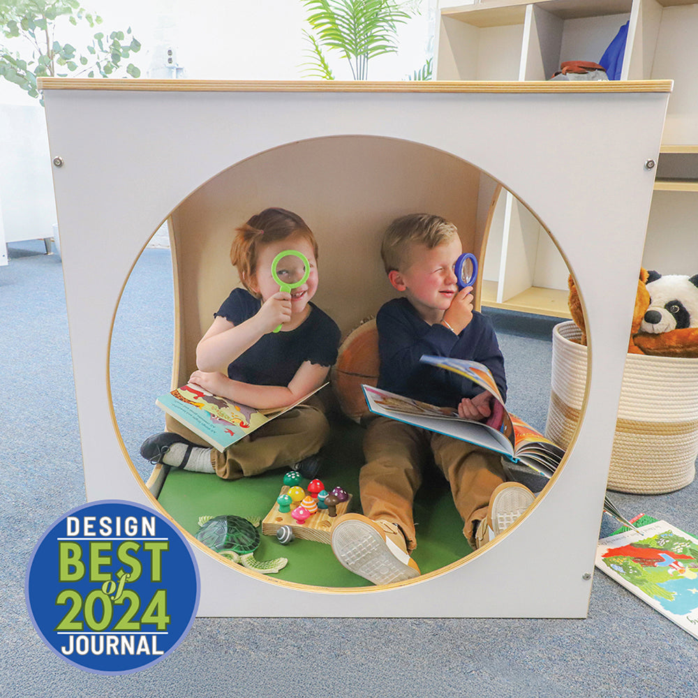 Two children playing with books and toys inside a circular playhouse with 'Best 2024' design award badge.