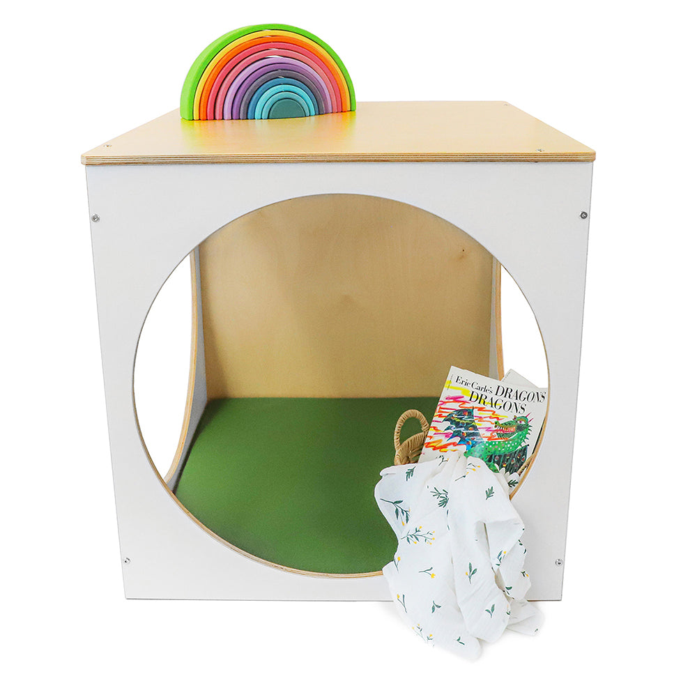Children's playhouse with rainbow discs, green mat, and book on a white background