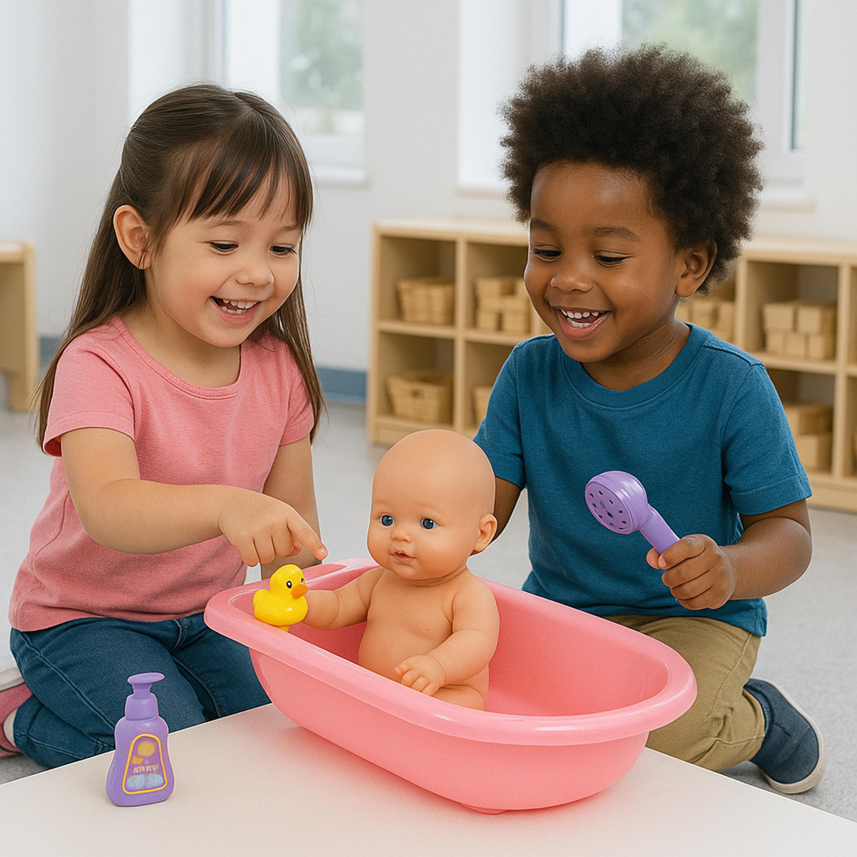 Two children playing with a baby doll in a pink bath tub on a white table, with a purple toy shower and a yellow rubber duck nearby in a bright indoor room.
