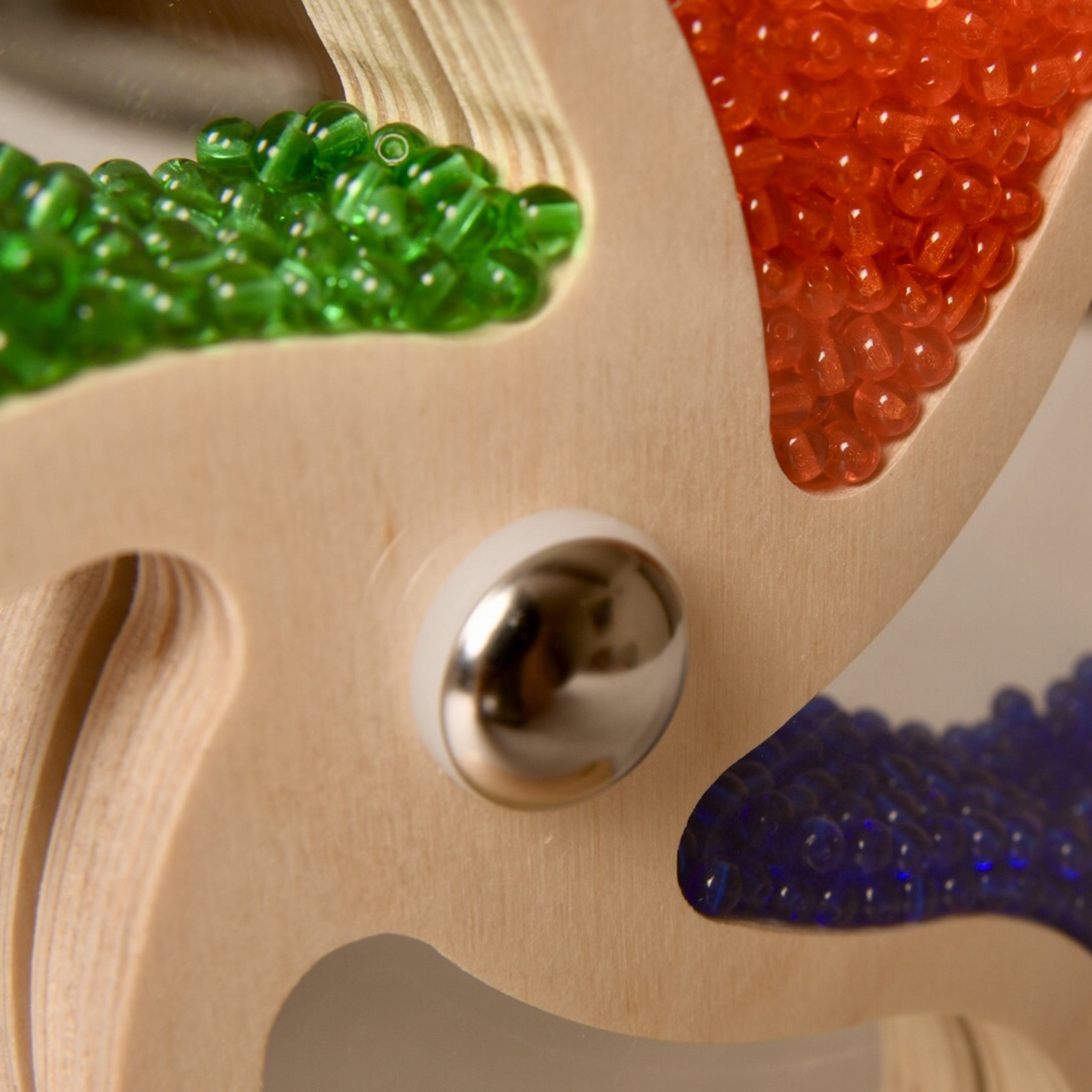 Close-up of a wooden toy with colorful beads and a metal ball.
