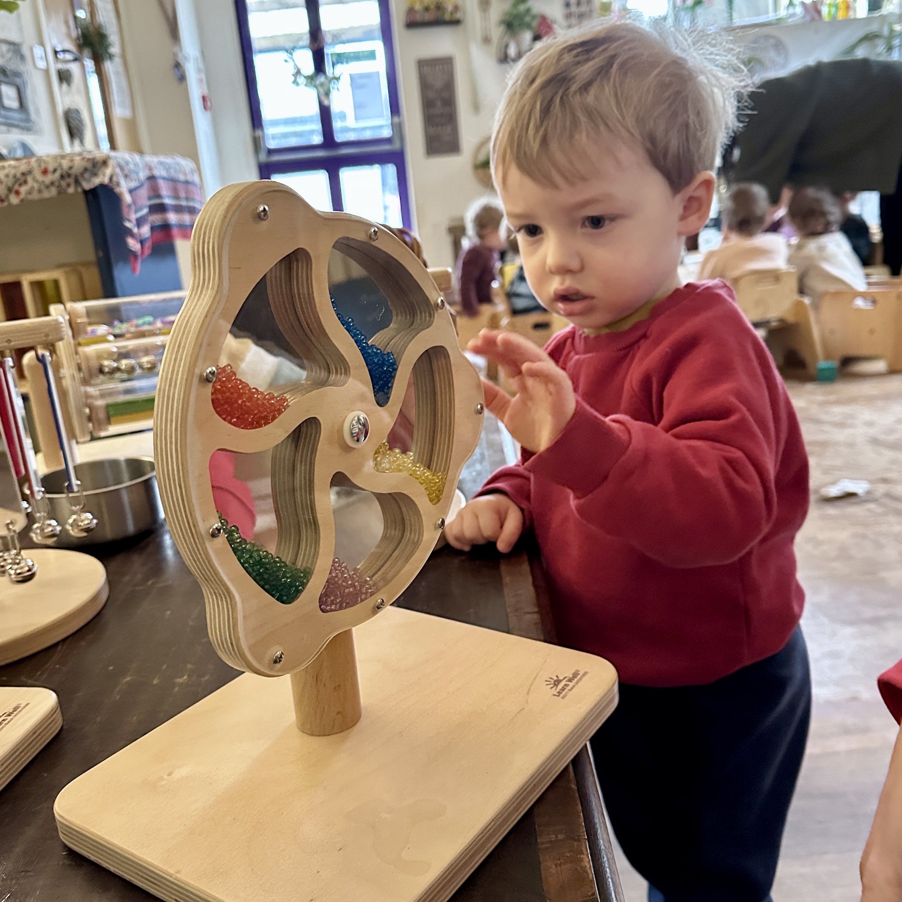 Child interacting with a wooden toy in a classroom setting