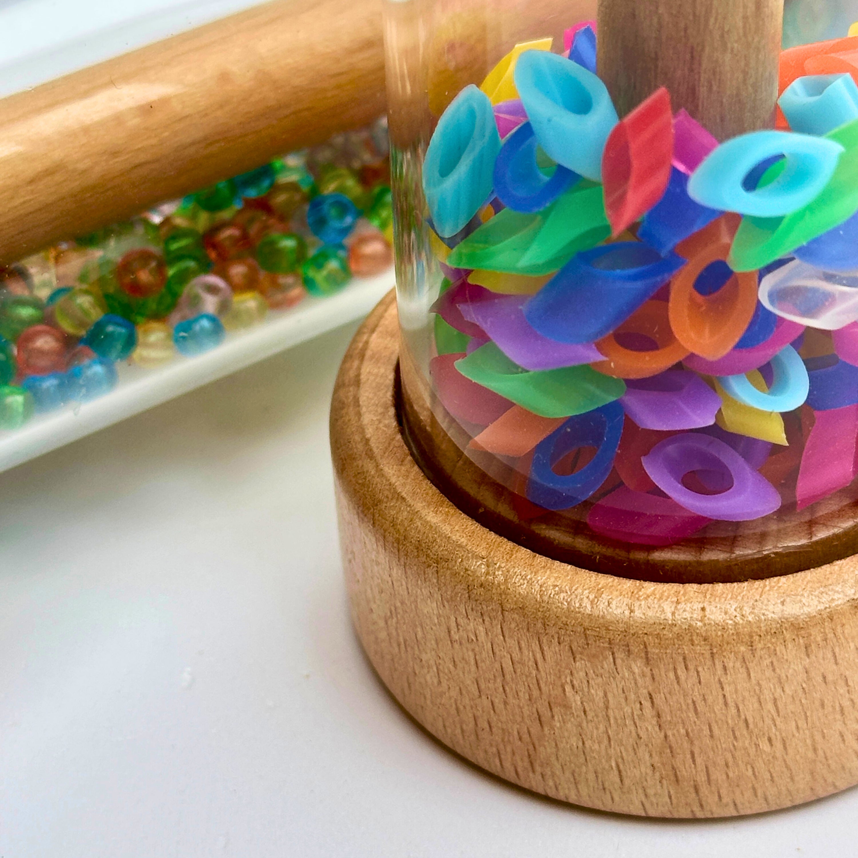 Colorful plastic pieces in a plastic tube with wooden lid on a white surface