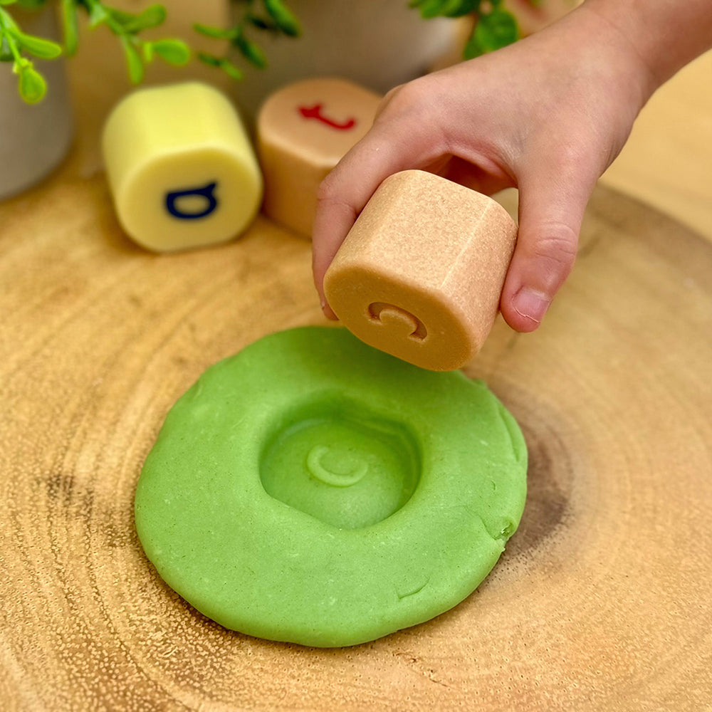Kid Pressing Letter C Alphabet Stone into Modeling Dough