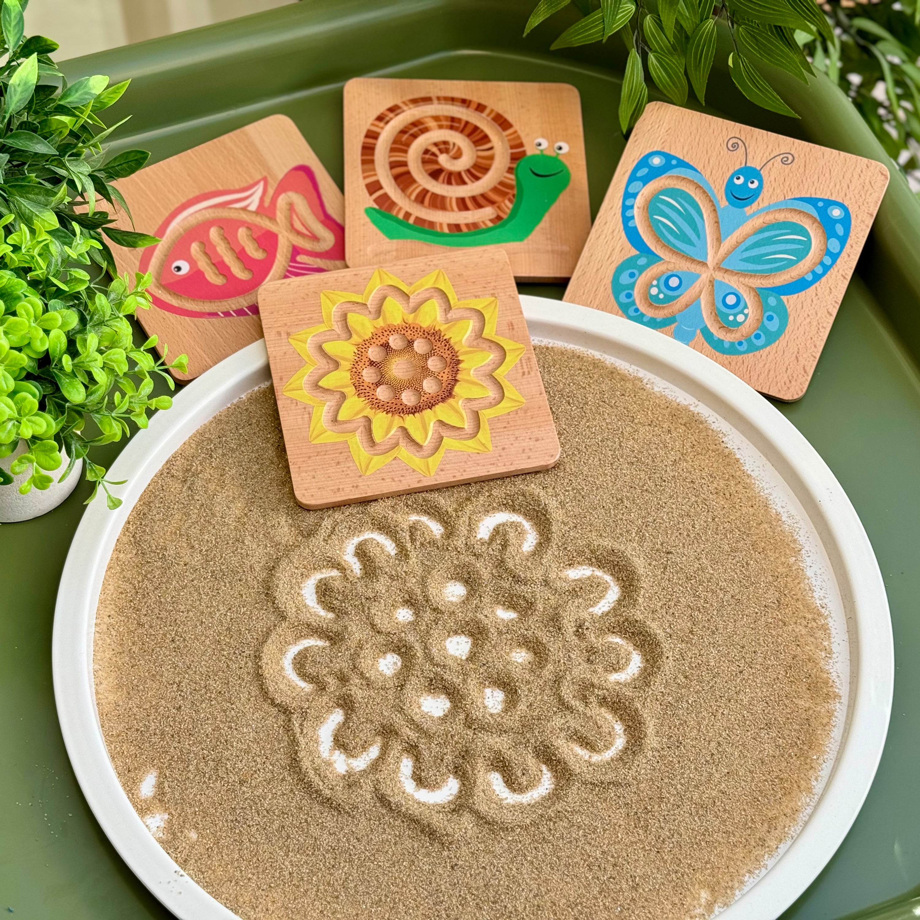 Set of wooden puzzles with animal designs on a sand tray