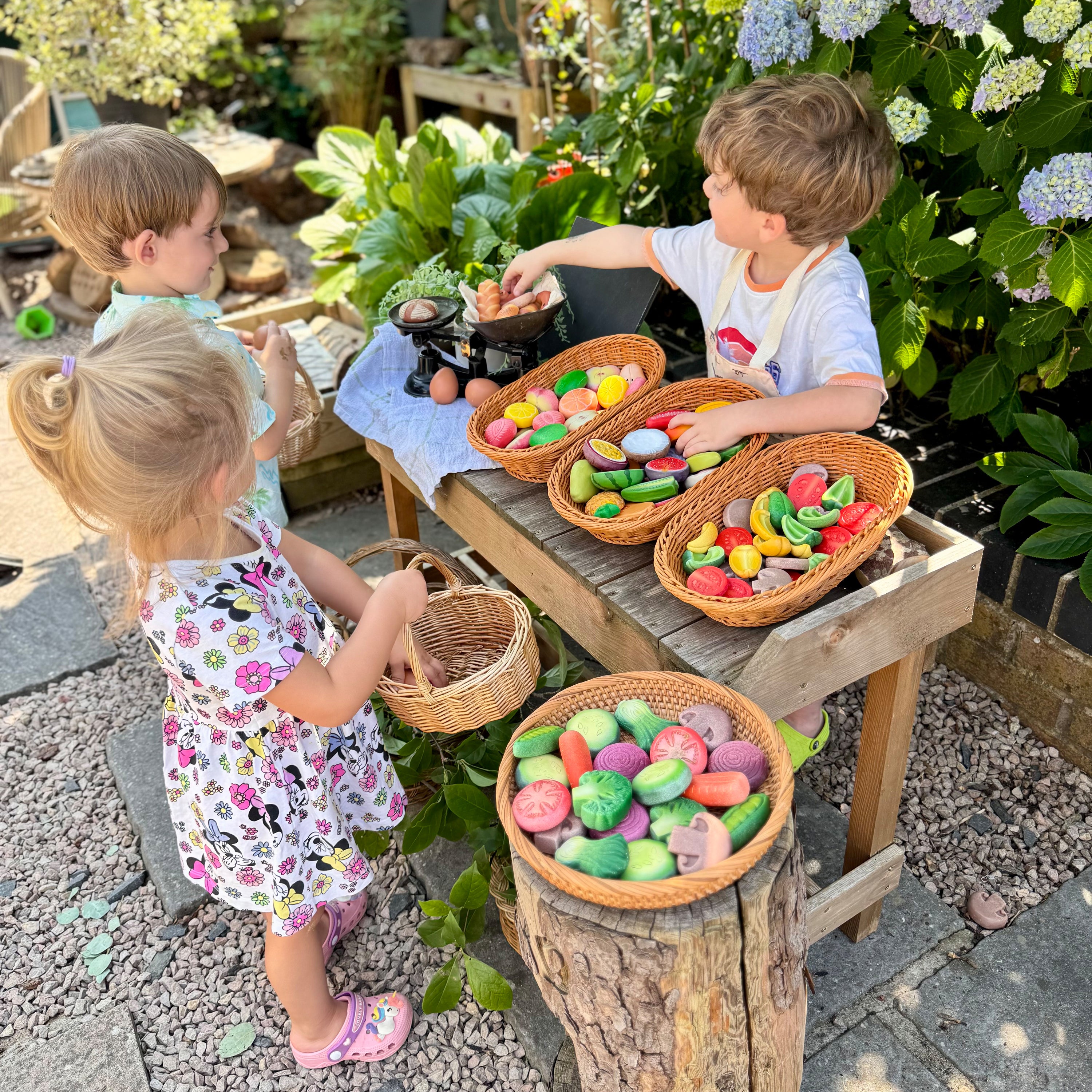 Children playing with colorful stones in baskets outdoors.
