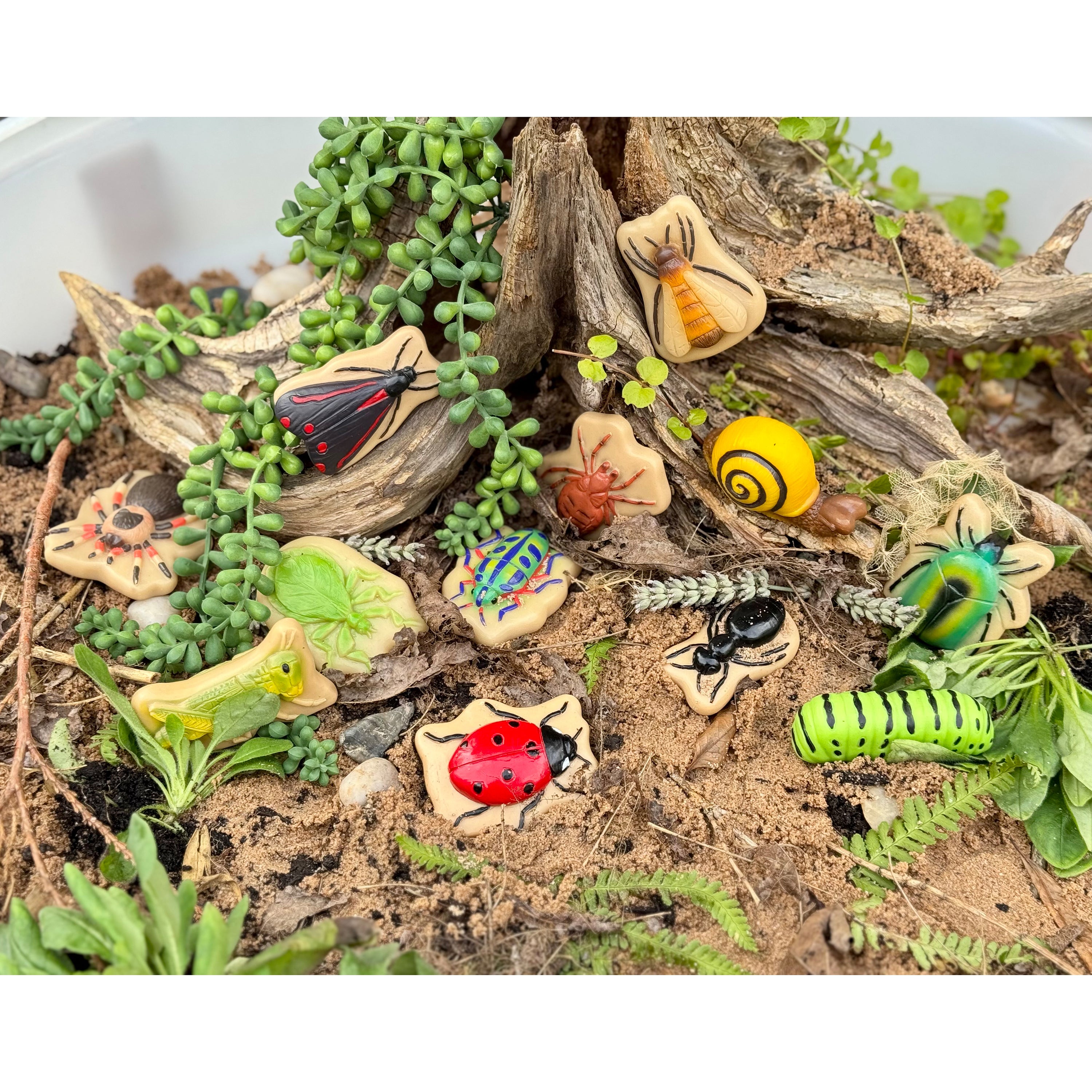 Miniature garden scene with various small figurines and plants on a white background