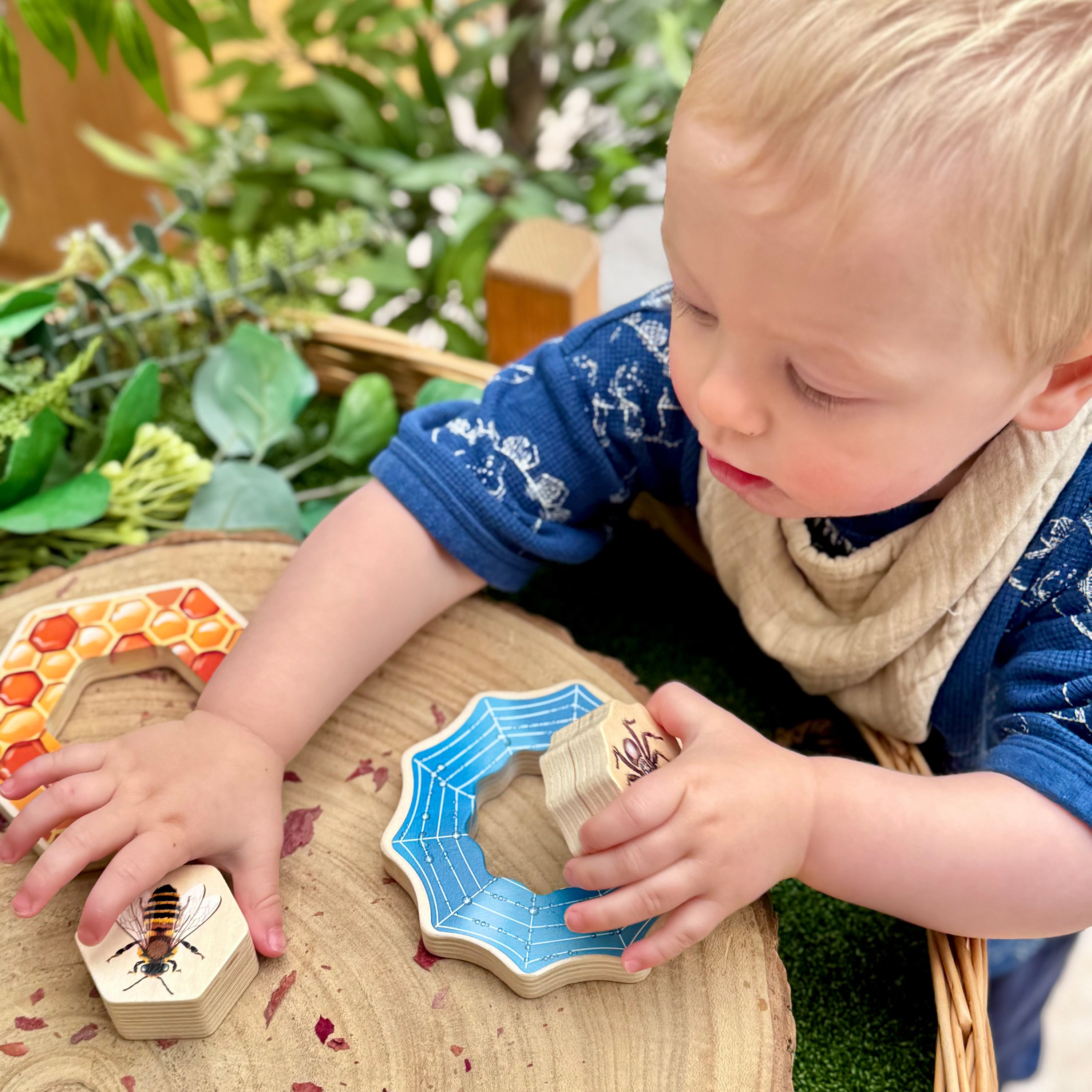 Child playing with wooden puzzle pieces on a table outdoors