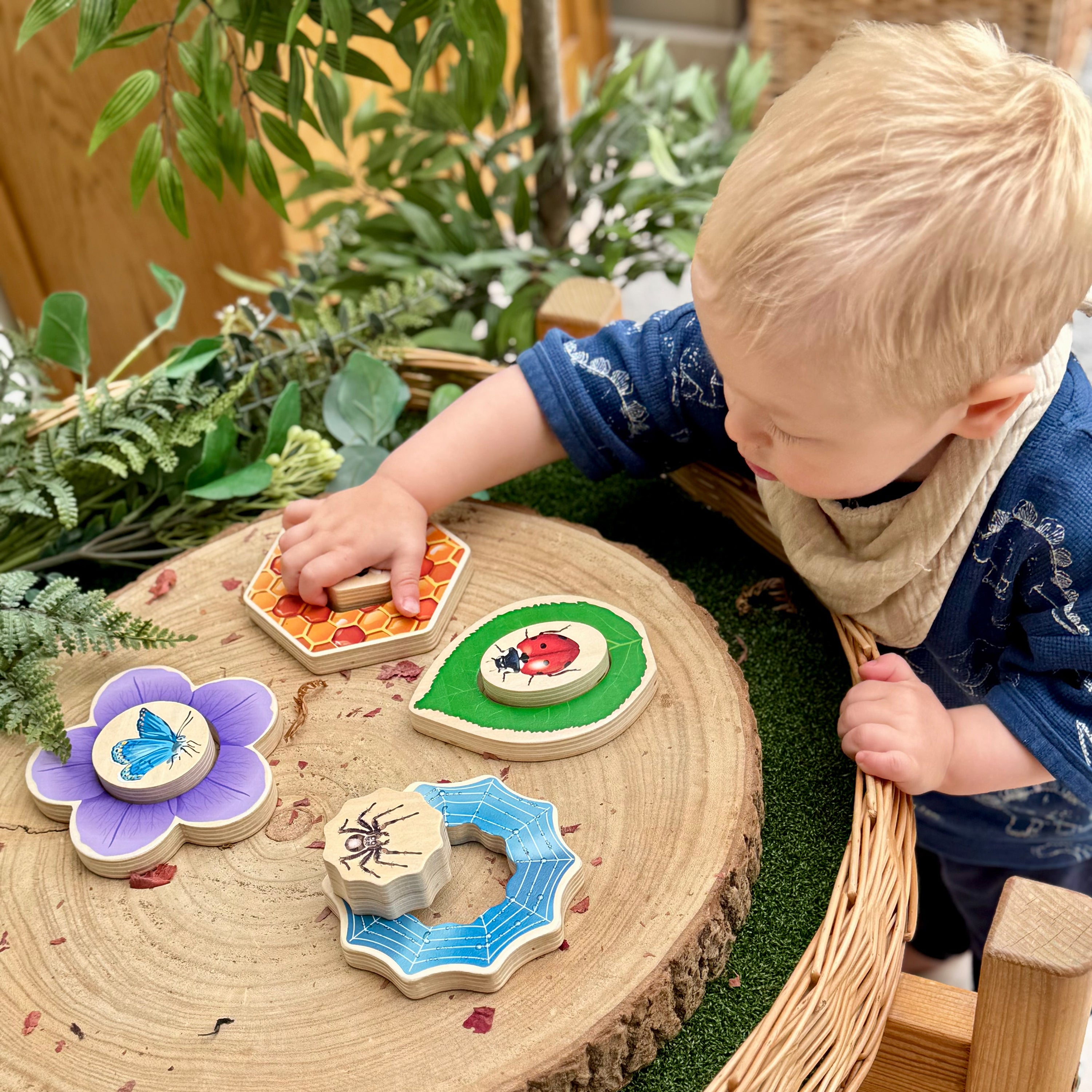 Child playing with wooden educational toys on a natural surface with plants in the background