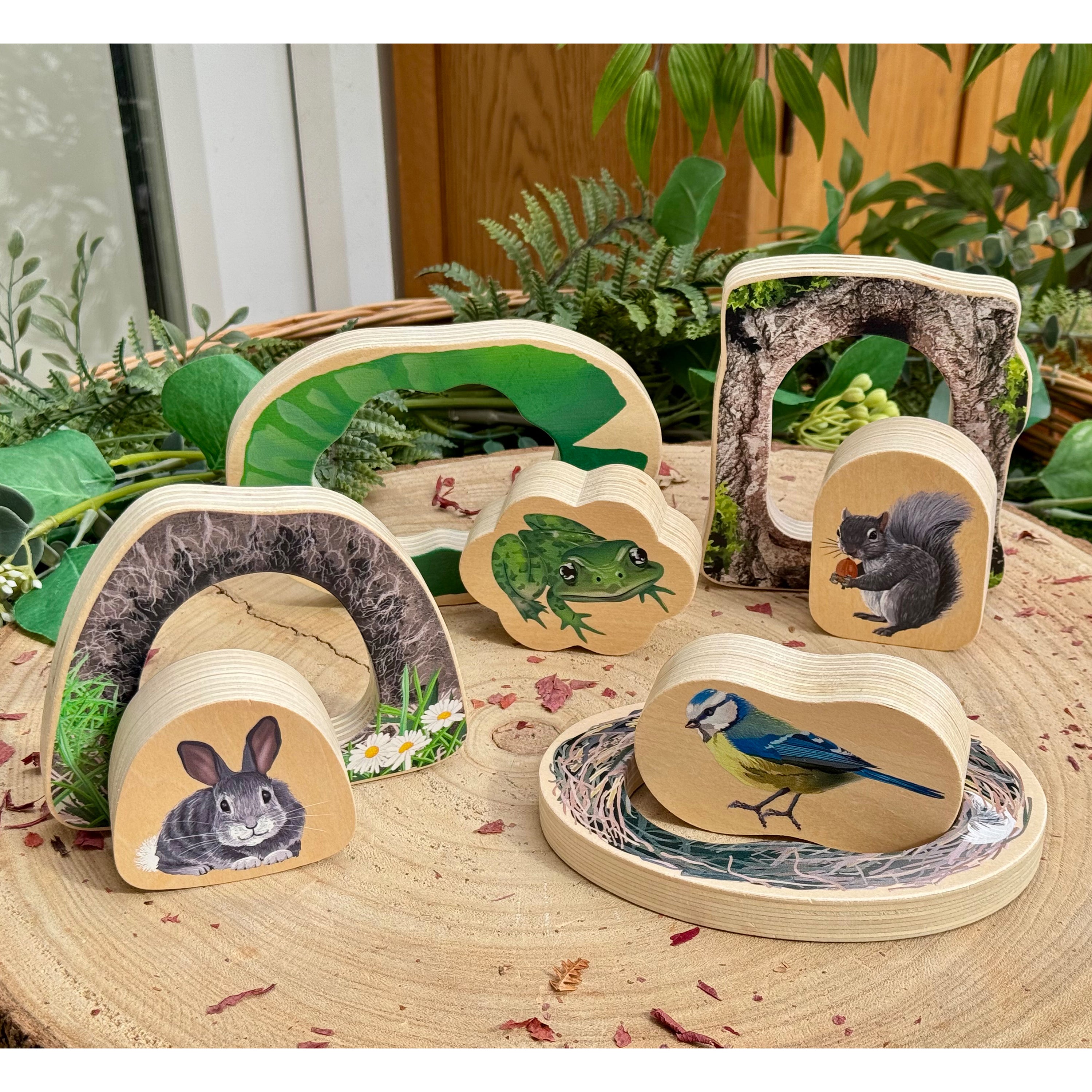 Wooden animal toys with naturalistic designs on a wooden surface with plants in the background