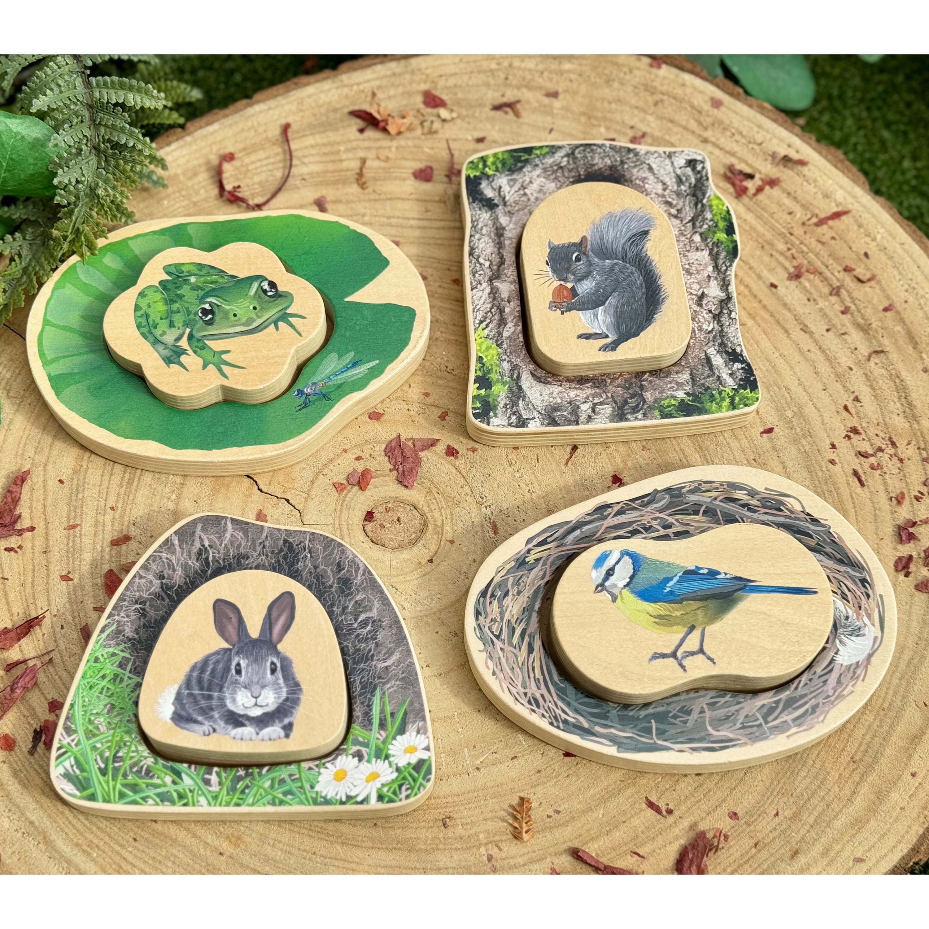 Set of wooden animal figurines on a natural wood surface with greenery.