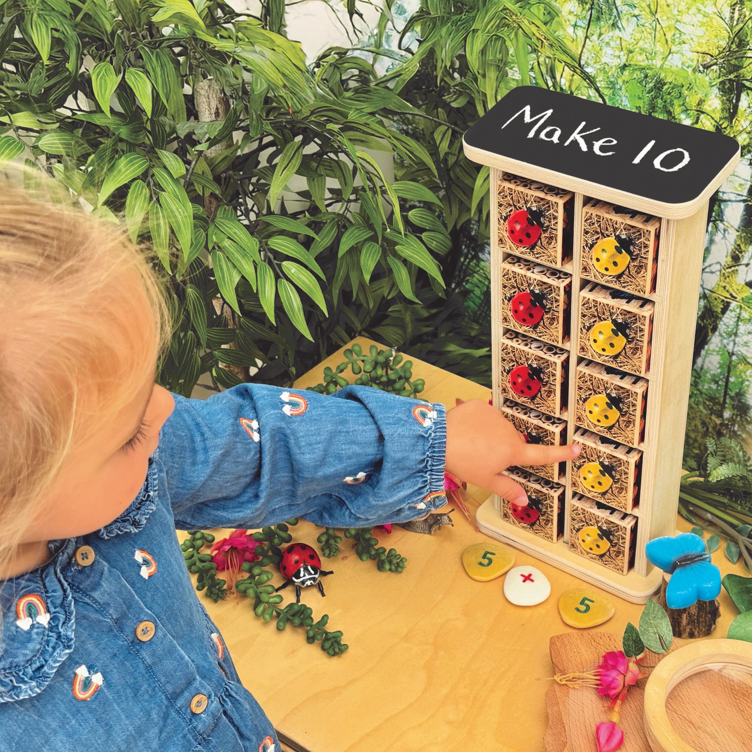 Child playing with a educational toy that has drawers labeled with numbers and colorful items on a wooden surface.