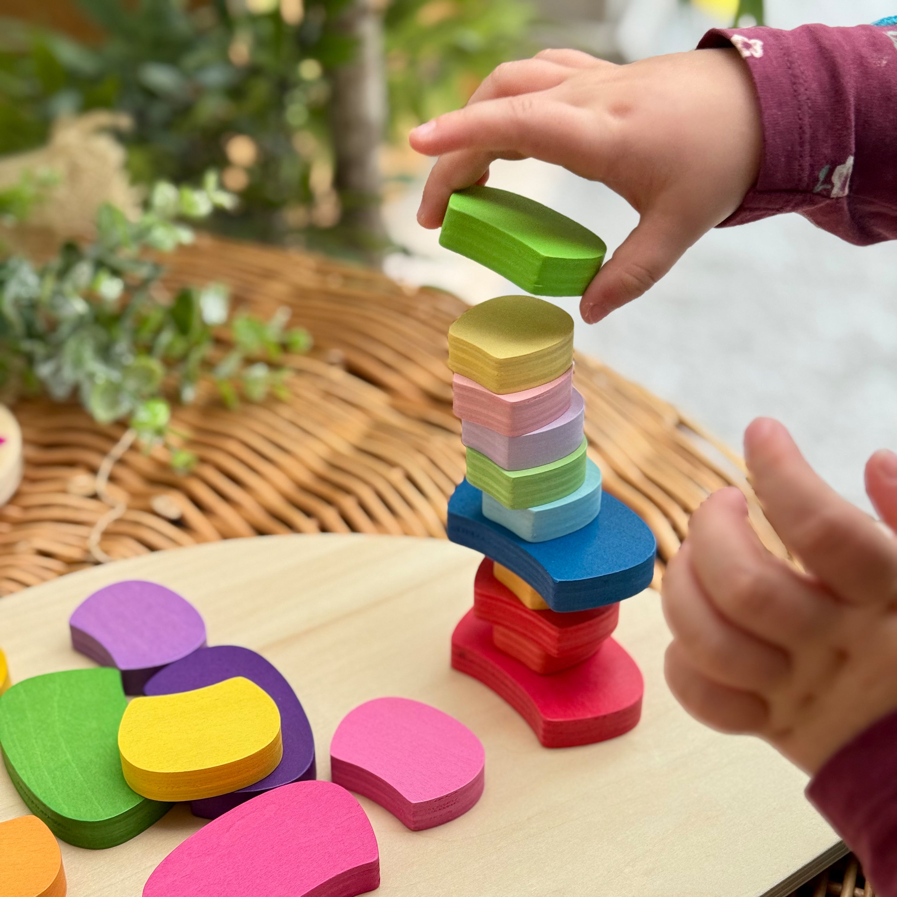Child playing with colorful wooden blocks on a table outdoors.