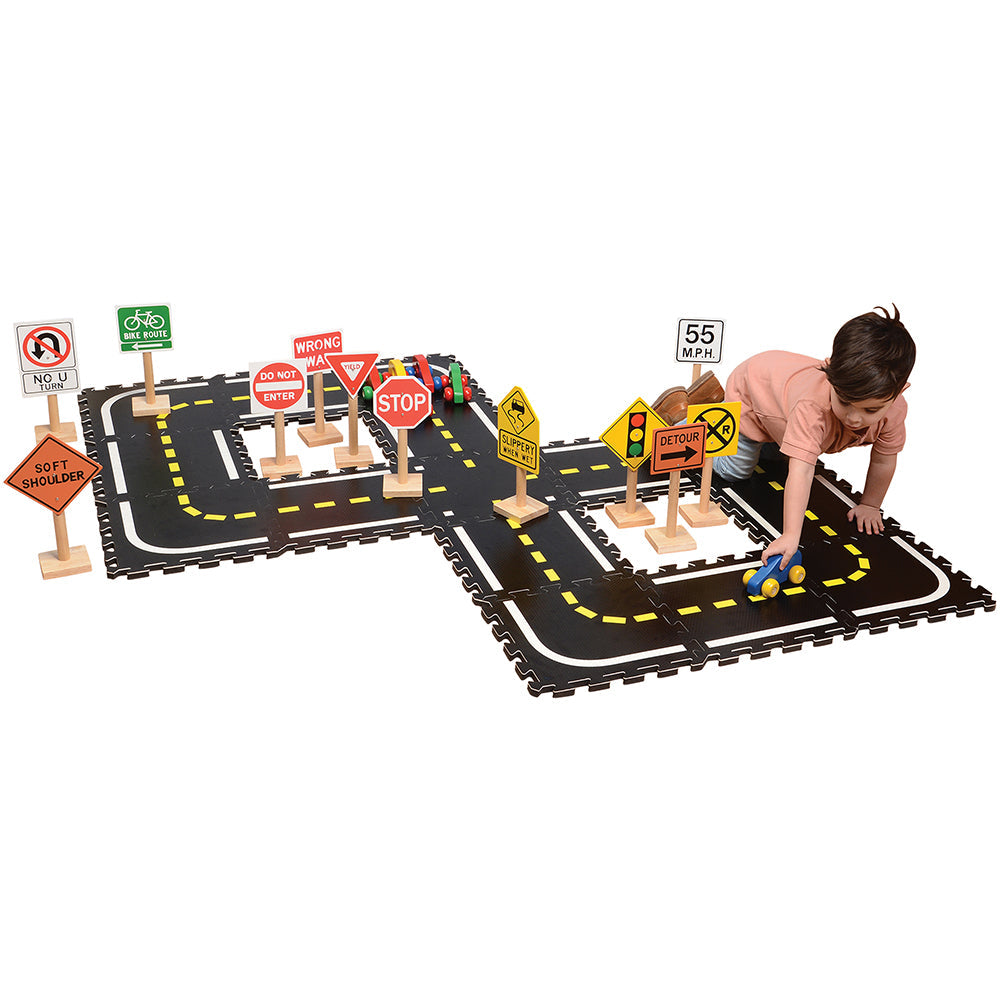 Kid Pushing A Car Along Foam Roadway with Wooden Street Signs