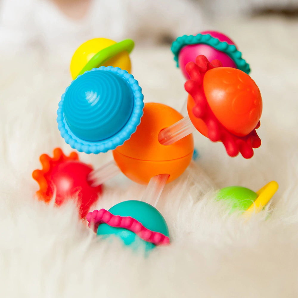 A colorful collection of infant toys with geometric patterns and silicone rings.