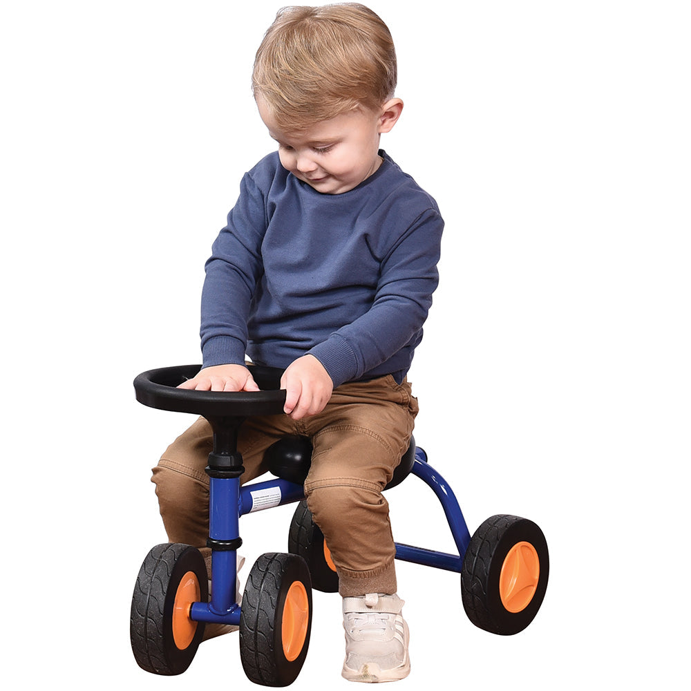 Toddler in blue shirt seated on blue trike with white background