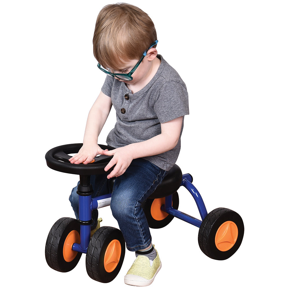 Toddler in gray shirt seated on blue trike with white background