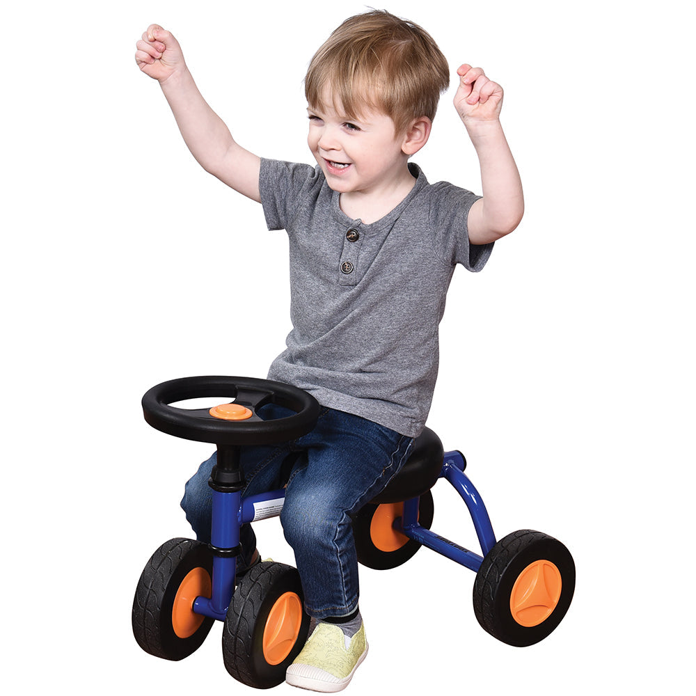 Toddler in gray shirt seated on blue trike with white background