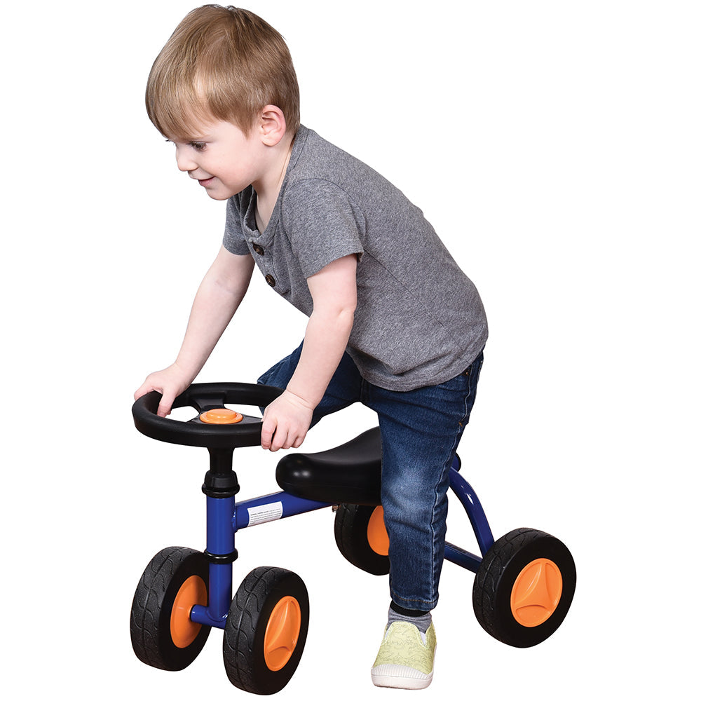 Toddler in gray shirt seated on blue trike with white background