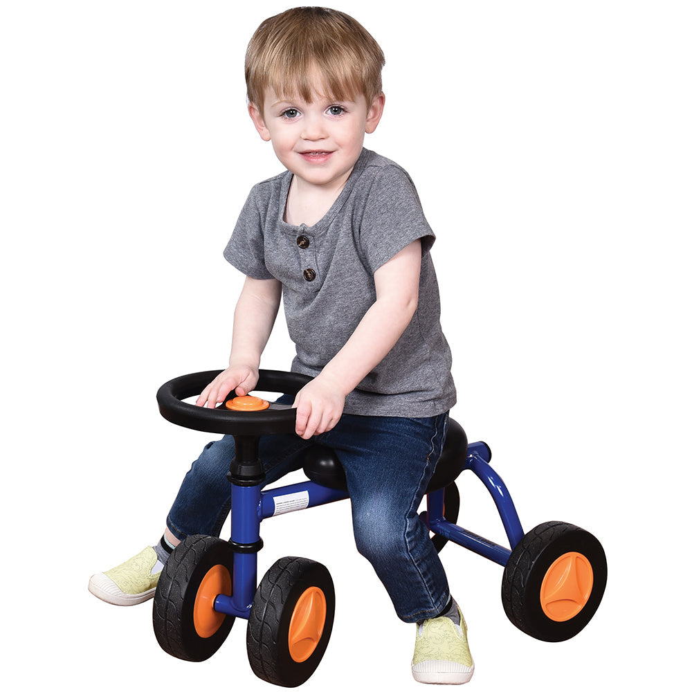 Toddler in gray shirt seated on blue trike with white background