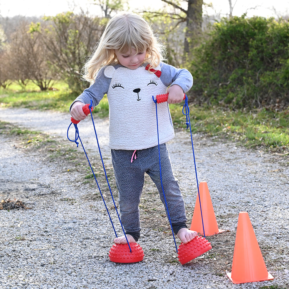 Kid Practicing Balance with Tactile Half-Sphere Stilts Outdoors