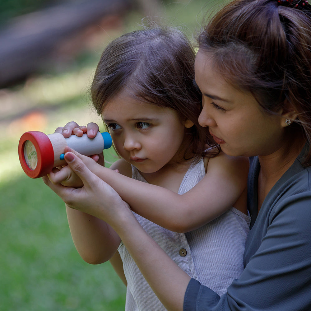 Adult Helping Kid Look At the World Through Kaleidoscope