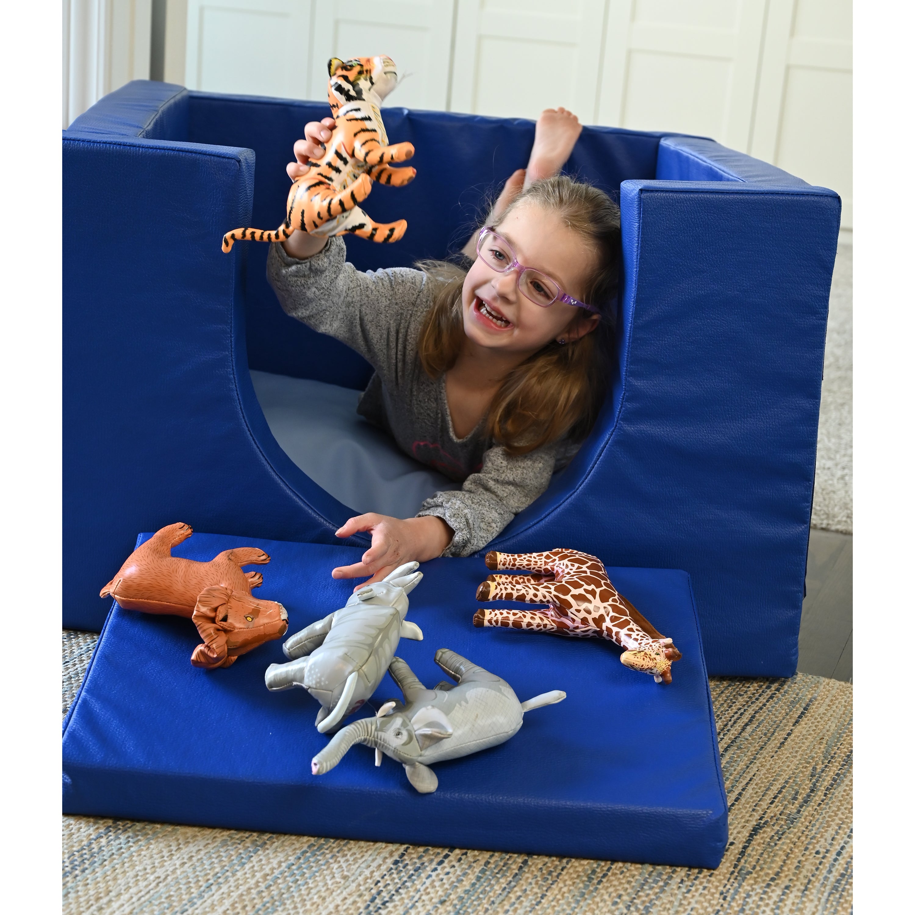 Kid in blue quiet cube playing with soft jungle animal figures