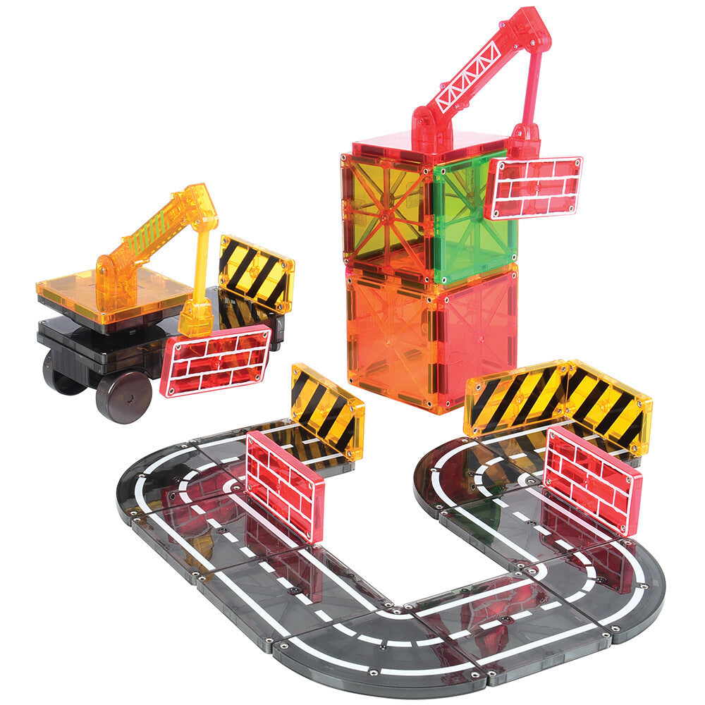 A collection of colorful Magna-Tiles set up to build a simple road and construction theme scene with magnetic cranes and road signs.