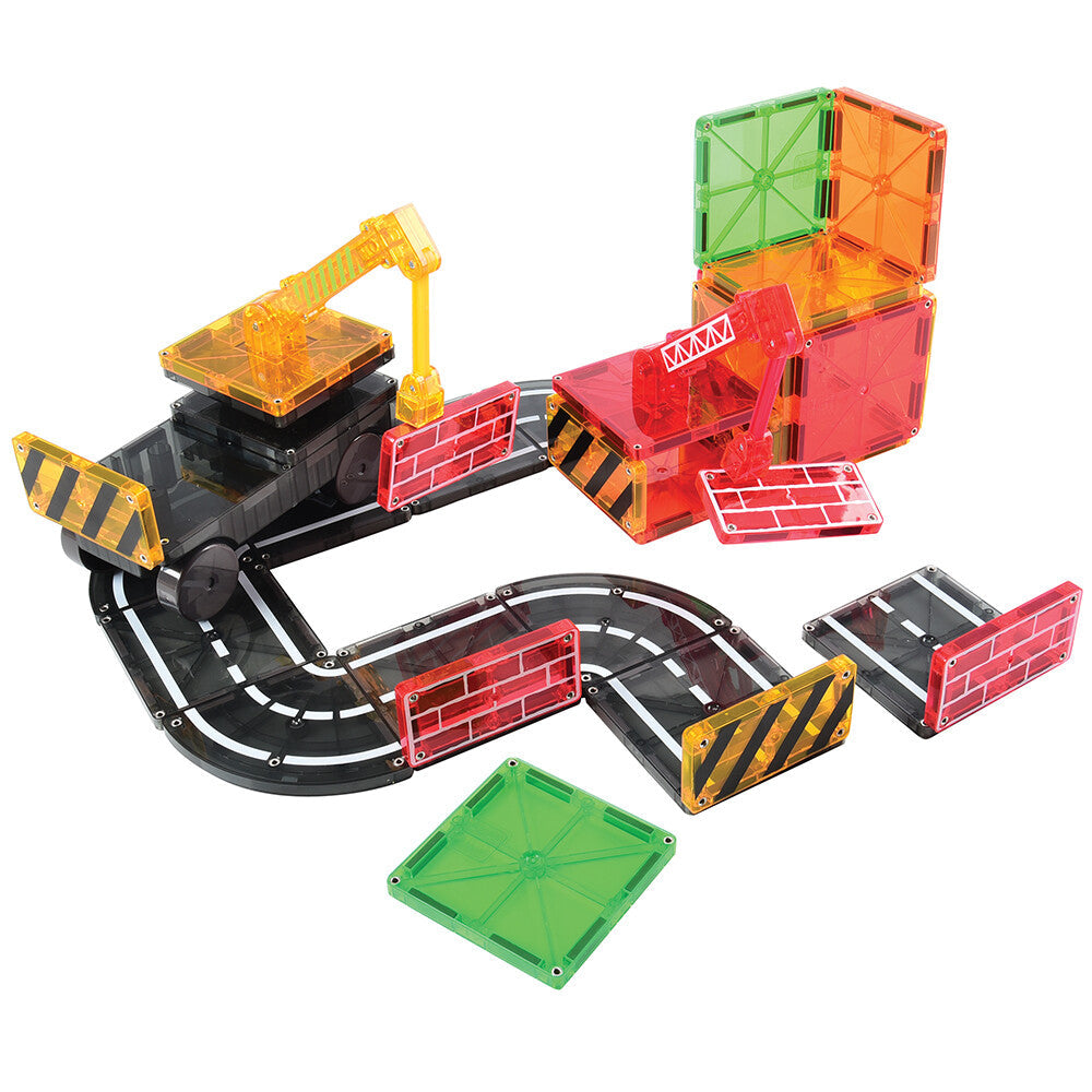 A collection of colorful Magna-Tiles set up to build a simple road and construction theme scene with magnetic cranes and road signs.